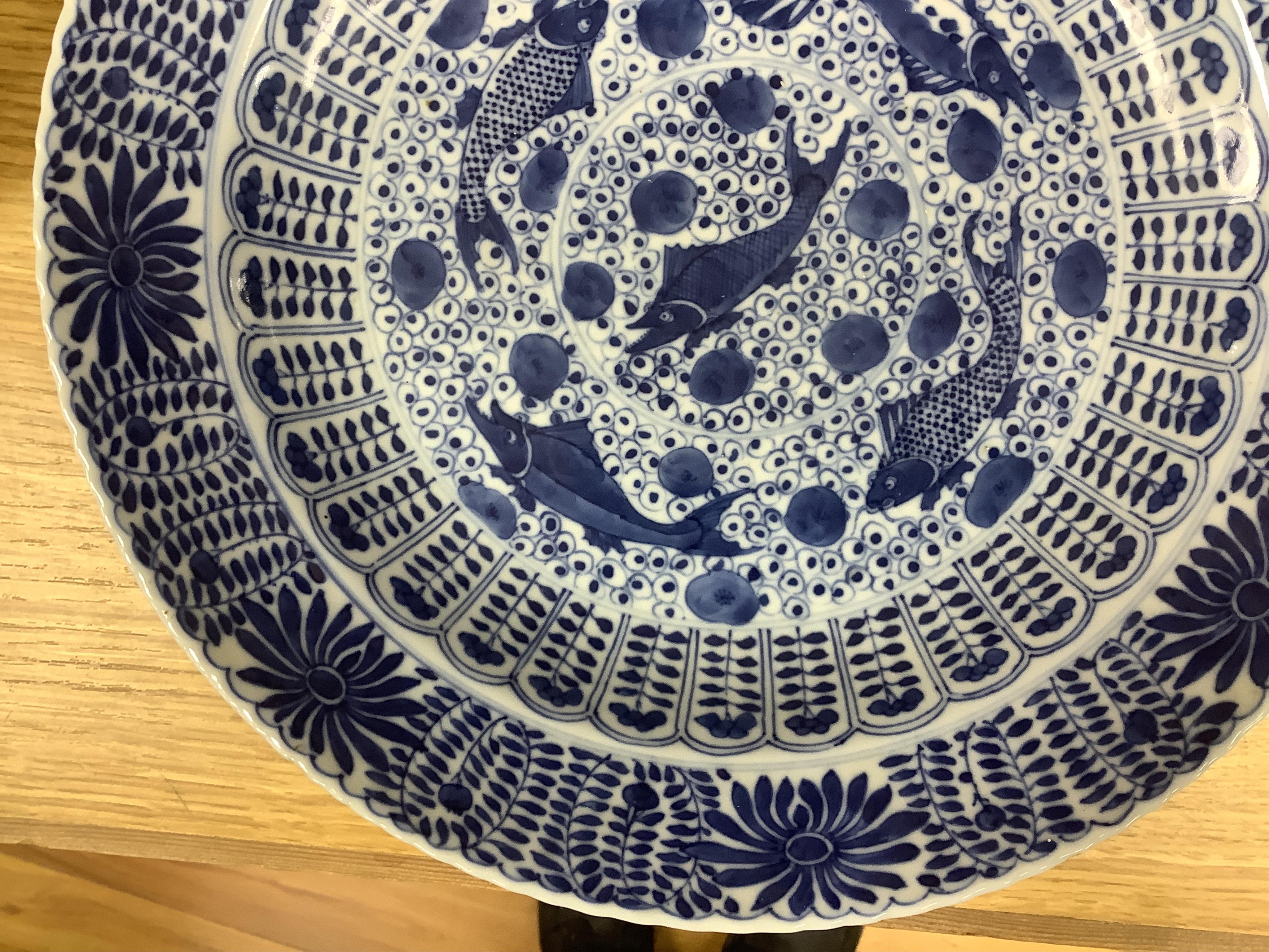 A Chinese blue and white 'fish' dish, Kangxi mark but c.1900, 33cm diameter. Condition - slight chipping to rim